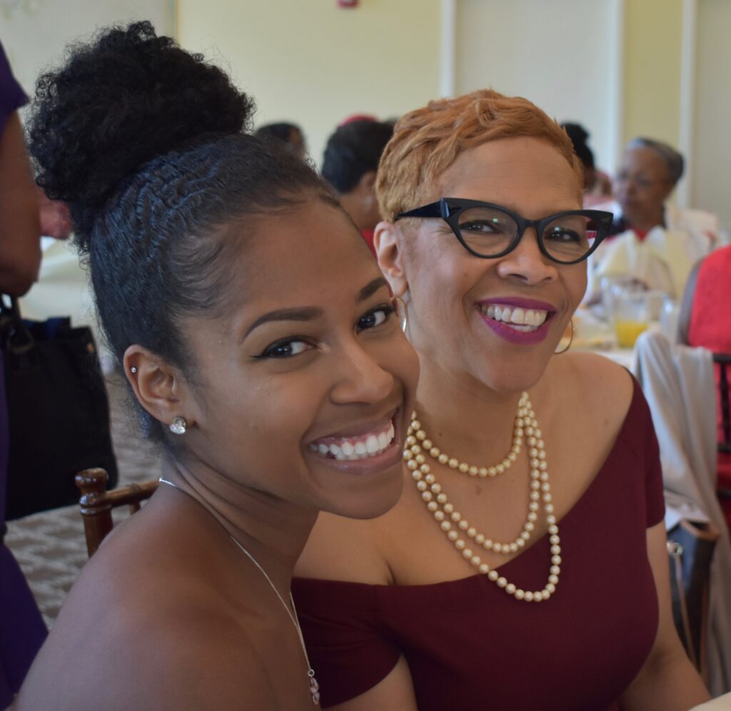 Two women smiling warmly at an event.