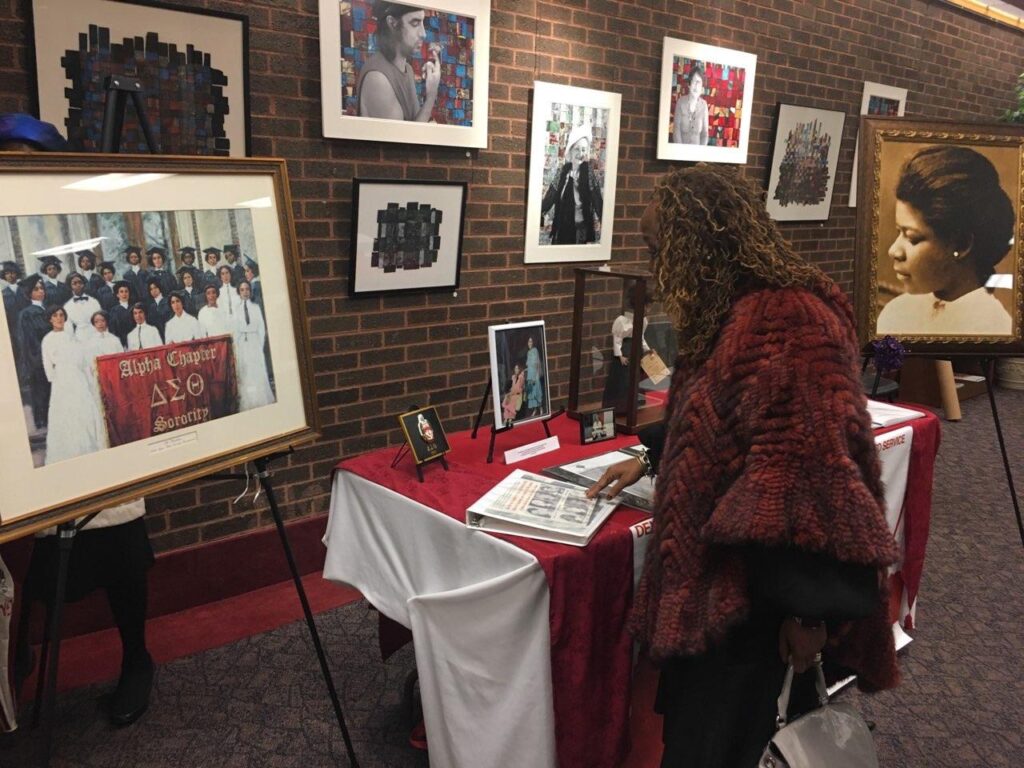 Woman signs a guestbook at a memorial display with framed photos and flowers.