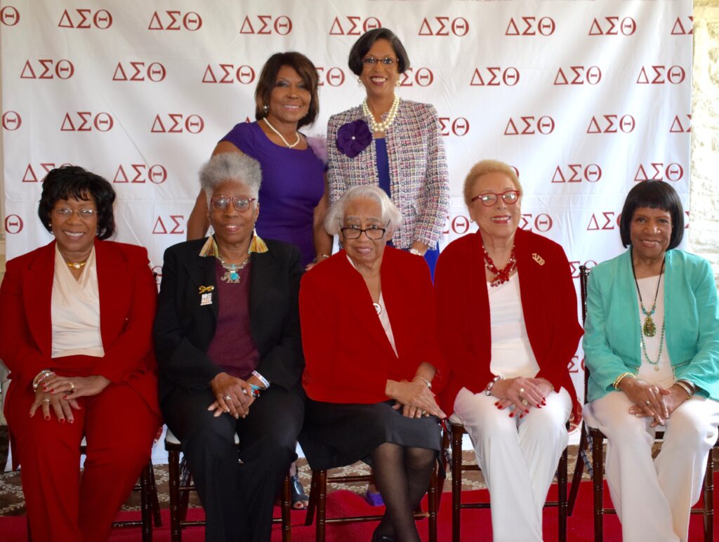 A group of elderly women posing together, some wearing Delta Sigma Theta attire.