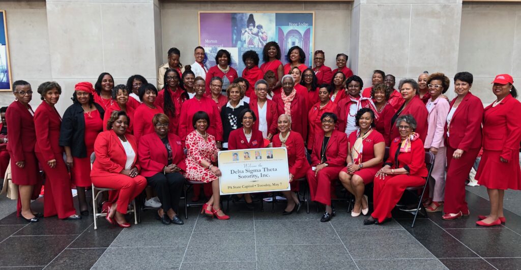 Group of women dressed in red holding a large check for breast cancer support.