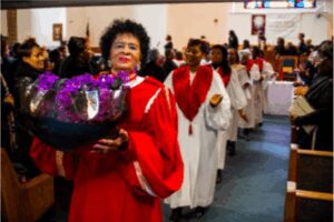 A choir procession in red robes inside a church.