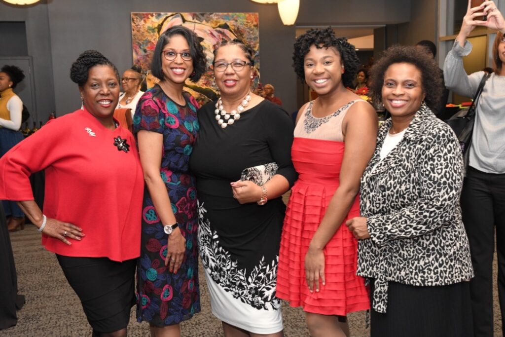 Group of five women posing together at an event.