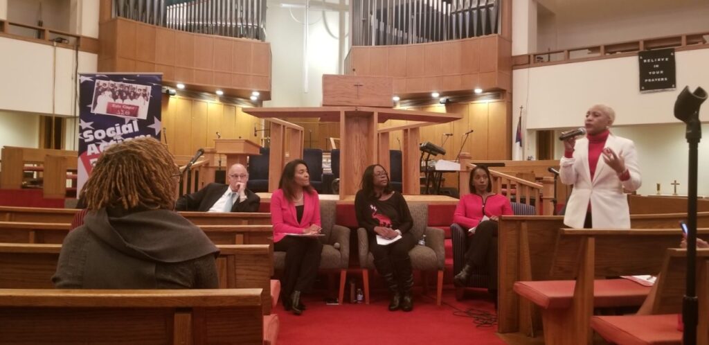 Four people seated in a church setting, two wearing pink.