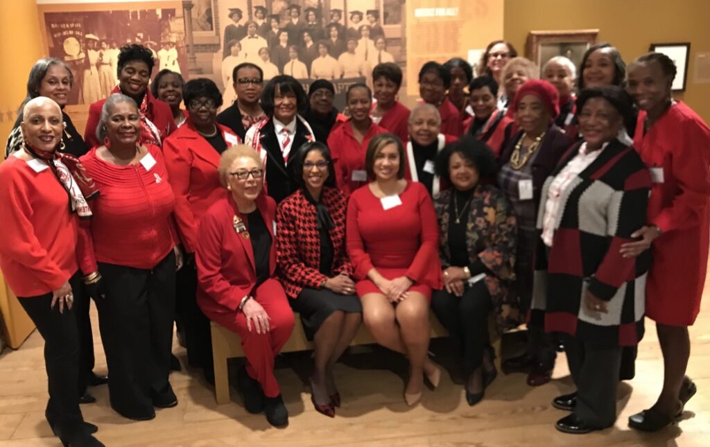 Group of women in red and black posing together indoors.