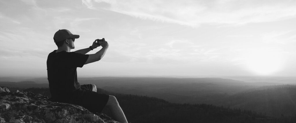 Person meditating outdoors overlooking a vast natural landscape.