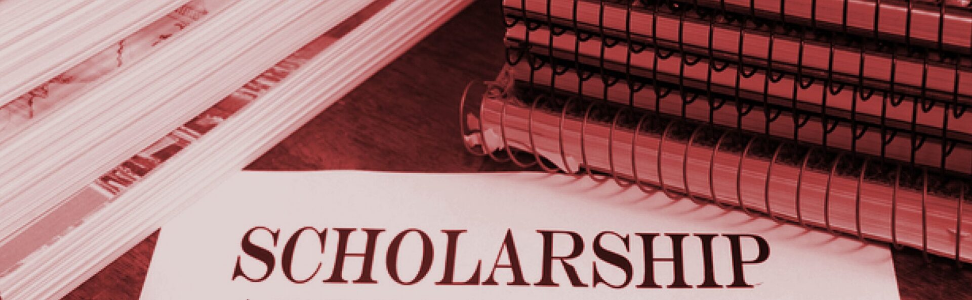 A close-up of the word 'SCHOLARS' on a paper with spiral notebooks.