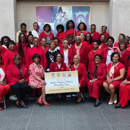 Group of women dressed in red holding a large check for breast cancer support.