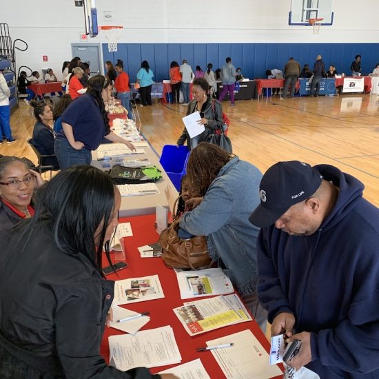 People engaging at a community event with informational tables and materials.
