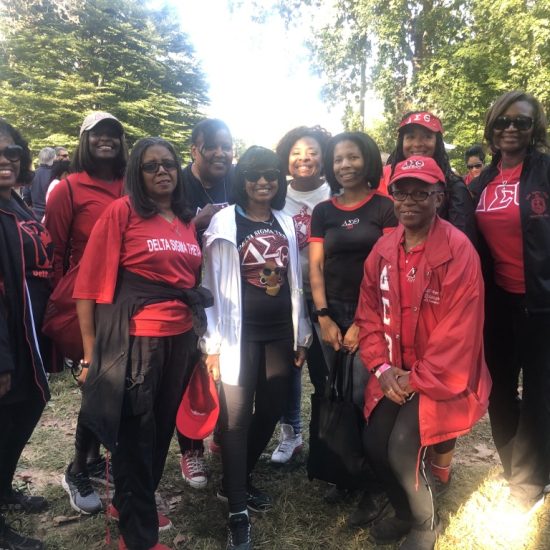 Group of people outdoors, many wearing red and smiling.