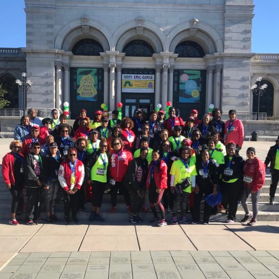 Large group posing outside a historic building on a sunny day.