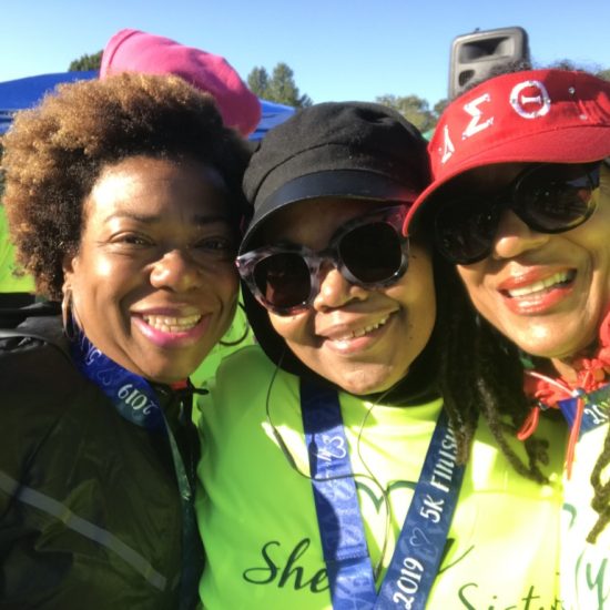 Three smiling women outdoors, enjoying a sunny day.