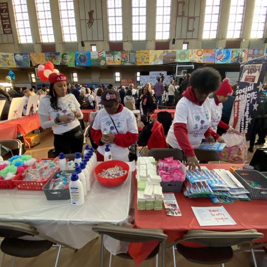 Volunteers preparing materials at a community event table.
