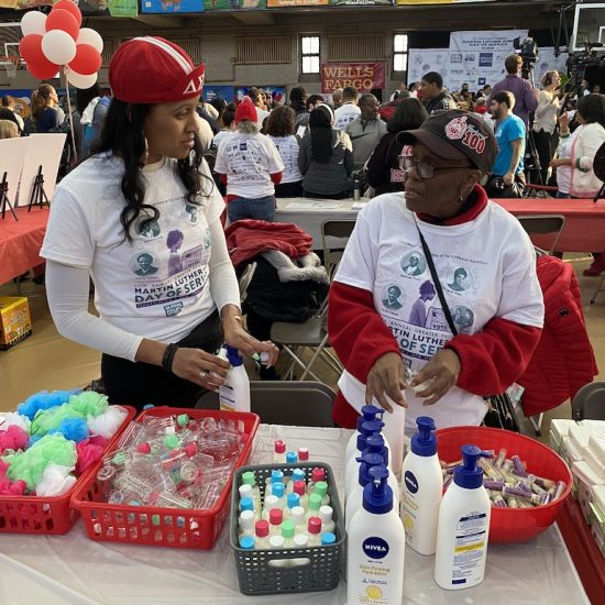 Two people selling colorful cotton candy and bottled drinks at an indoor event.