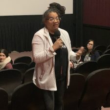 A woman speaking into a microphone in a theater.