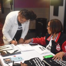 Two women engaged in paperwork at a table with documents and pens.