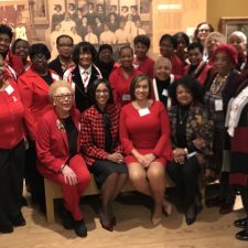 Group of women in red and black posing together indoors.