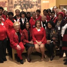 Group of women in red and black posing together indoors.